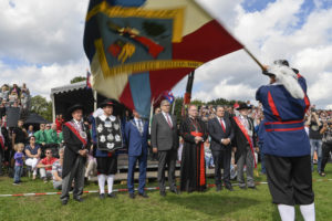 Een vendelier zwaait  buiten met een vlag voor publiek.