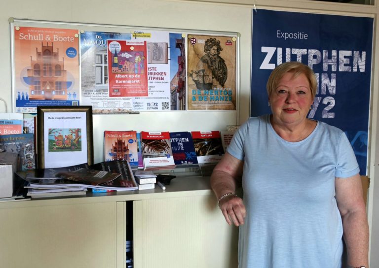 Erfgoedvrijwilliger Ria staat naast een kast waar folders, magazines en posters op uitgestald zijn