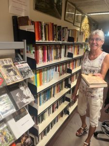 Mevrouw met een boek voor een grote boekenkast.