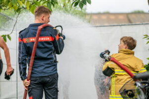 De brandweer spuit de deelnemers schoon na de race