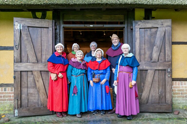Vrijwilligers van Museum Klooster Ter Apel in kostuum voor de openslaande deuren